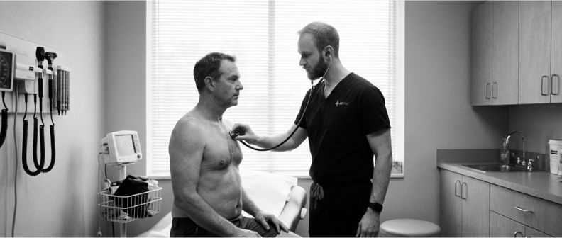 Dr. Tom from AllWell Men's Health Clinic administering a private health check to a male patient aged 55+.